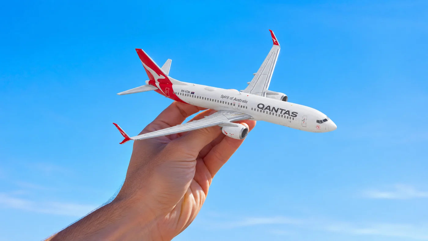 A Qantas model aircraft held against a blue sky